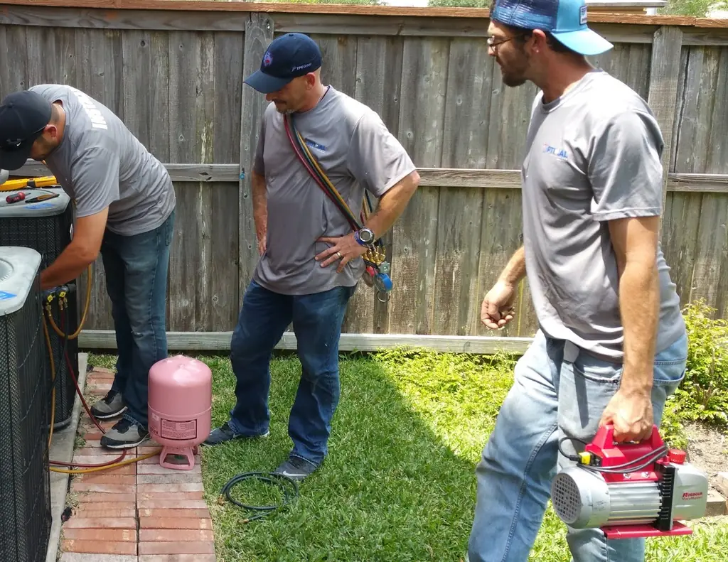 Three Optimal Air Solutions technicians in branded shirts working a residential job